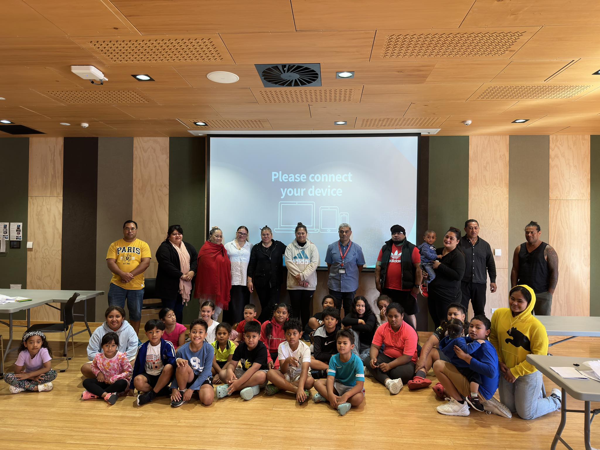 Full group of island people standing in front of a screen